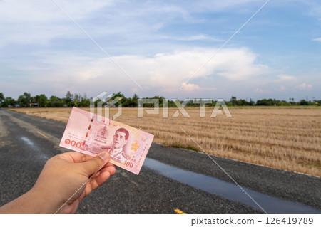 Hand holding currency note in rural landscape thailand open field wide angle economic concept 126419789
