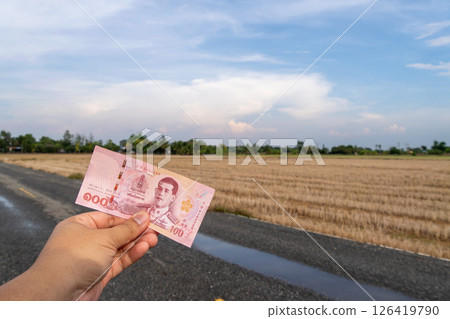 Holding a banknote in a rural landscape thailand daytime close-up currency value 126419790