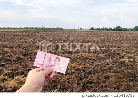 Currency in hand agricultural land economic exchange rural area ground level financial transactions 126419792