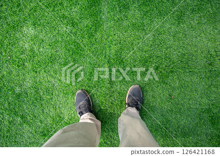 Cropped shot view of someone standing on green artificial turf. Cropped shot view of someone standing on green artificial turf. 126421168