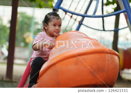 happy toddler girl riding jet ski toy at playground 126421531