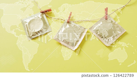 Condoms hanging on clothesline over world map image 126422789