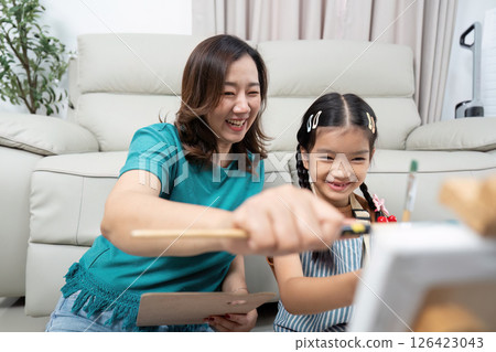 Activity joyful mother and daughter painting together in their home 126423043