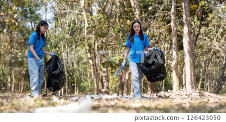 Volunteers collecting garbage in a forest, demonstrating teamwork and commitment to environmental cleanup 126423050