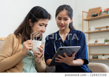 Caregiver showing health information on a tablet to an elderly patient Caregiver showing health information on a tablet to an elderly patient 126423108
