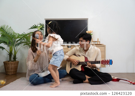 Musical Moments and Family Joy. A daughter interacting with her parents during a musical session. 126423120