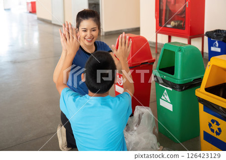 Playful Learning and Recycling. A child and a teacher share joy while learning about waste sorting. 126423129