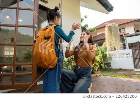 Warm Farewell Before School. A mother gives her daughter a cheerful send-off. 126423200