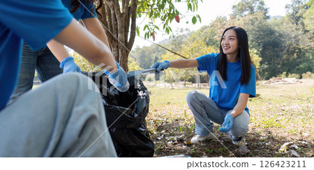 Young volunteer crouching to collect trash during a community cleanup, promoting environmental care 126423211