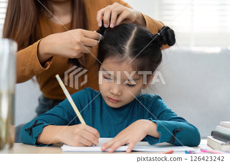 Support and Learning. A caring adult helps a girl with her homework. 126423242