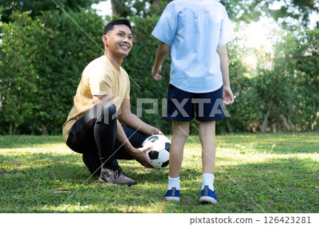 Wellness through bonding: Father playing soccer with son outdoors Wellness through bonding: Father playing soccer with son outdoors 126423281