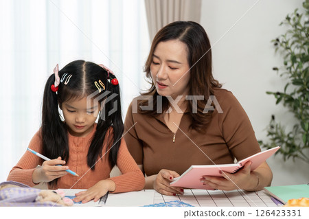Mother and Daughter Back to School. Engaging study session with mother helping daughter with homework. 126423331