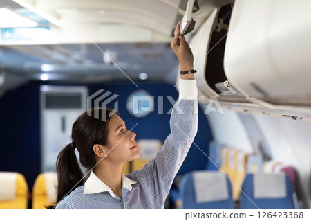 Business travel preparation with airline personnel organizing overhead luggage 126423368