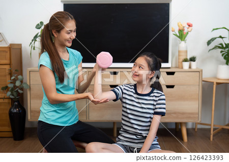 Mother and Daughter Fitness. Sharing a Fun Weightlifting Moment at Home. Mother and Daughter Fitness. Sharing a Fun Weightlifting Moment at Home. 126423393