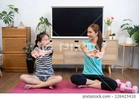 Mother and Daughter Wellness. Engaging in Stretching Exercises at Home. Mother and Daughter Wellness. Engaging in Stretching Exercises at Home. 126423410