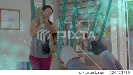 Image of glowing spots over diverse girls practicing air yoga Image of glowing spots over diverse girls practicing air yoga 126423719