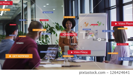 Image of media icons over diverse colleagues discussing work in office Image of media icons over diverse colleagues discussing work in office 126424641