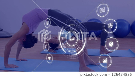 Woman practicing yoga, digital interface icons image over exercise studio Woman practicing yoga, digital interface icons image over exercise studio 126424886