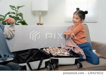 Family Bonding and Packing. A child and parent joyfully preparing for a travel adventure together by packing clothes. Family Bonding and Packing. A child and parent joyfully preparing for a travel adventure together by packing clothes. 126425632