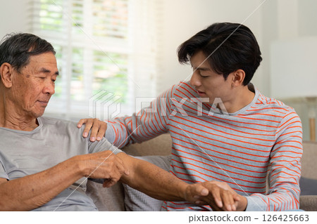 Young man comforting his elderly father with a gentle touch at home. 126425663