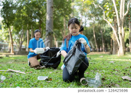Focused family volunteers collecting garbage in a park, emphasizing environmental responsibility and teamwork. 126425696