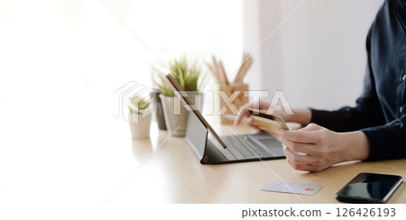 Close up hand of woman holding credit card and using laptop computer at home. Online shopping concept Close up hand of woman holding credit card and using laptop computer at home. Online shopping concept 126426193