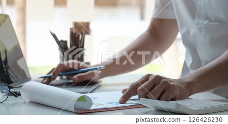 man accountant analyzing financial graph data with calculator man accountant analyzing financial graph data with calculator 126426230