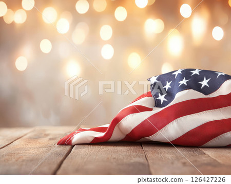 American flag draped on wooden table with bokeh background, evoking patriotism and celebration 126427226