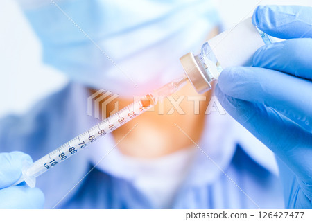 doctor's hand holds a syringe and a blue vaccine bottle at the hospital. Health and medical concepts. 126427477