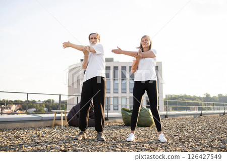 Senior man and woman outdoors on rooftop performing stretching exercises. Image promotes fitness healthy habits and active lifestyle among older adults emphasizing balance flexibility and well-being Senior man and woman outdoors on rooftop performing stretching exercises. Image promotes fitness healthy habits and active lifestyle among older adults emphasizing balance flexibility and well-being 126427549