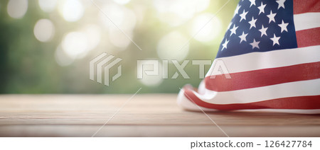 American flag draped on wooden table, symbolizing patriotism and freedom 126427784