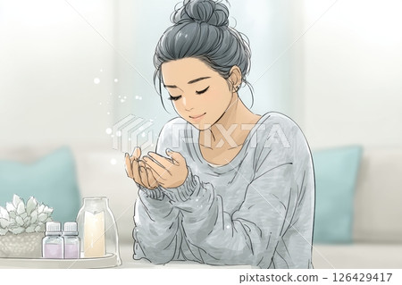 Young woman in cozy sweater sitting indoors with closed eyes and cupped hands, glowing sparkles floating above palms, peaceful atmosphere with candles and essential oils nearby 126429417
