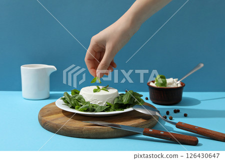 Ricotta in a bowl with herbs on a light background 126430647