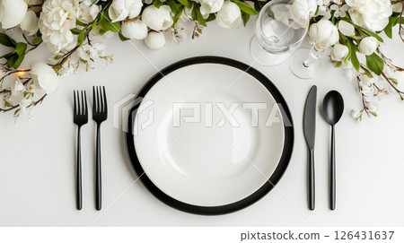festive table setting with elegant black and white dinnerware, surrounded by beautiful white flowers, perfect for special occasion 126431637