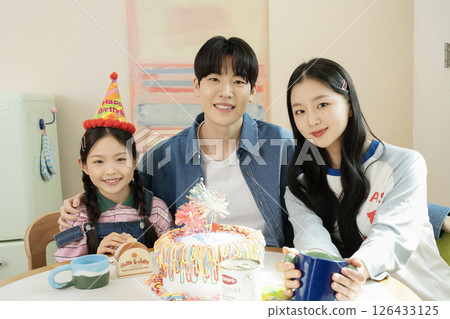 A family preparing a delicious cake for their daughter's birthday 126433125