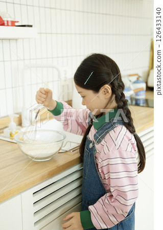 A child whipping bubbles with a whisk A child whipping bubbles with a whisk 126433140