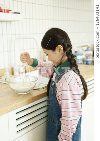 A child whipping bubbles with a whisk 126433141