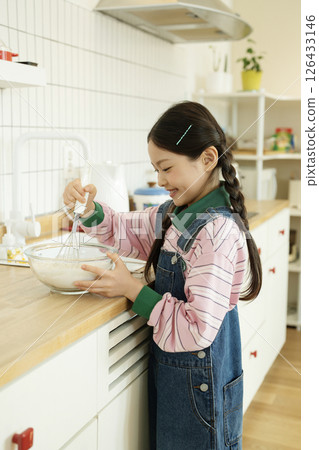 A child whipping bubbles with a whisk 126433146