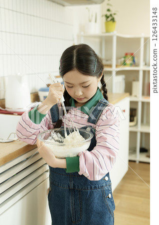 A child whipping bubbles with a whisk 126433148