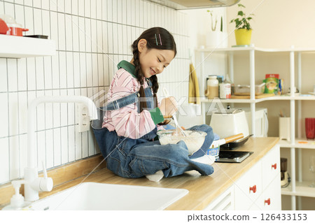 A child climbing on the sink and whipping bubbles with a whisk 126433153