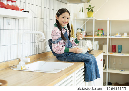 A child climbing on the sink and whipping bubbles with a whisk 126433155