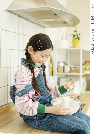 A child climbing on the sink and whipping bubbles with a whisk 126433156