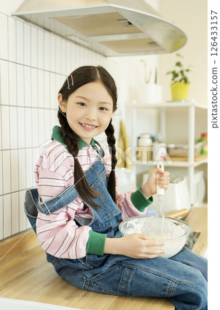 A child climbing on the sink and whipping bubbles with a whisk 126433157