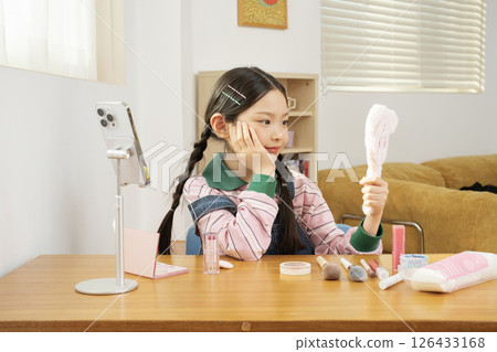 A cute child YouTuber who shoots beauty vlog content while holding his smartphone upright. 126433168