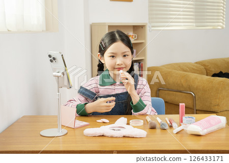 A cute child YouTuber who shoots beauty vlog content while holding his smartphone upright. 126433171