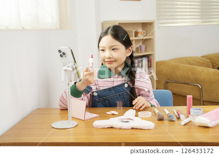 A cute child YouTuber who shoots beauty vlog content while holding his smartphone upright. 126433172