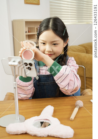 A cute child YouTuber who shoots beauty vlog content while holding his smartphone upright. 126433191