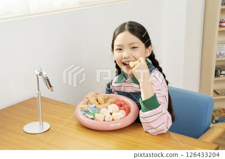 A cute child YouTuber who stands up on his smartphone and films a mukbang 126433204