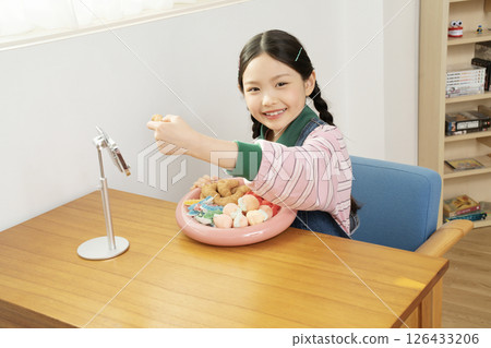 A cute child YouTuber who stands up on his smartphone and films a mukbang 126433206