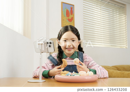 A cute child YouTuber who stands up on his smartphone and films a mukbang A cute child YouTuber who stands up on his smartphone and films a mukbang 126433208